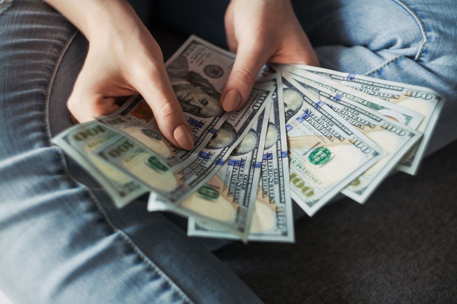 A person holds a bunch of $100 bills.